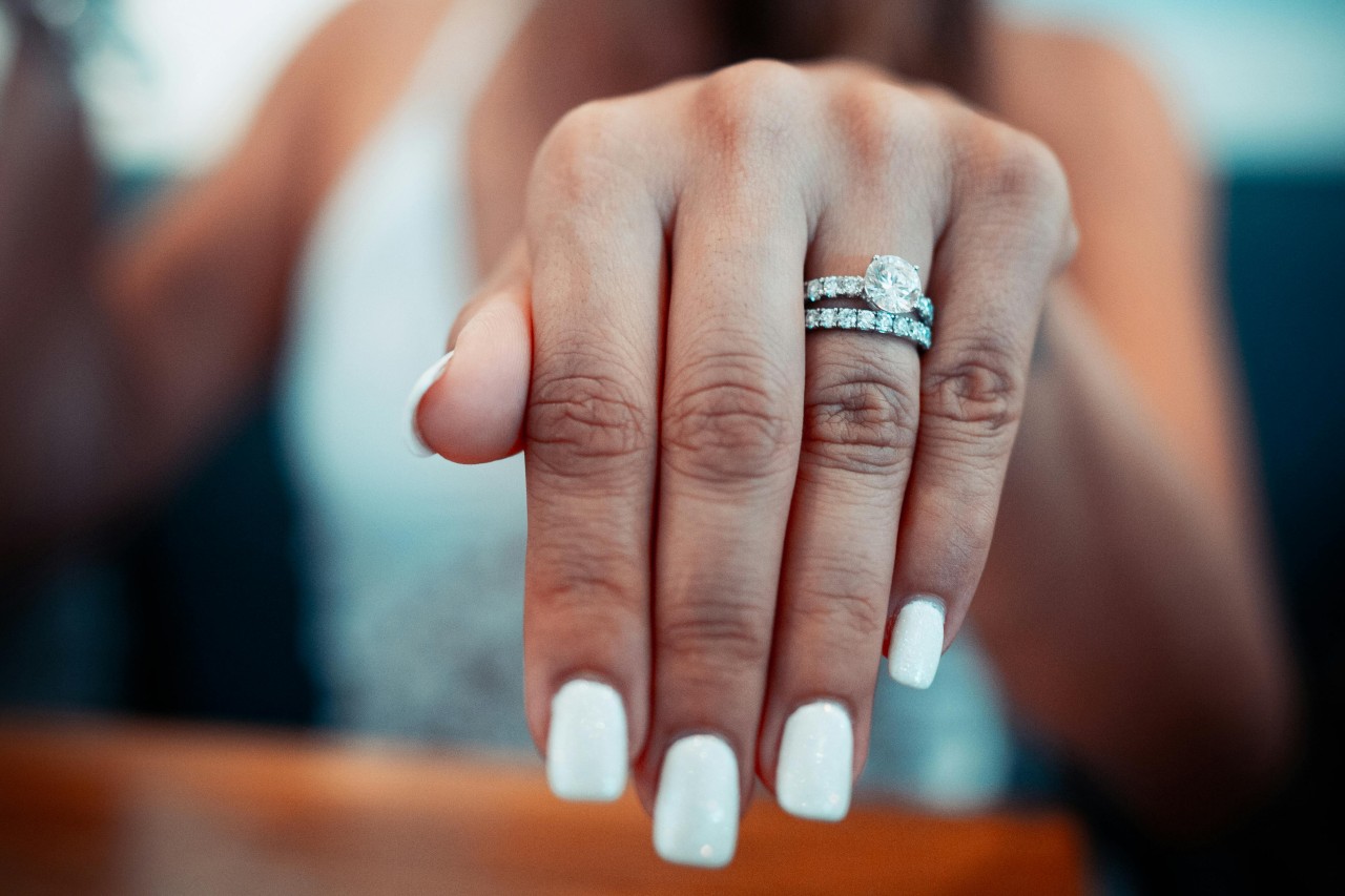 a woman extending her hand to show off a matching engagement ring and wedding band