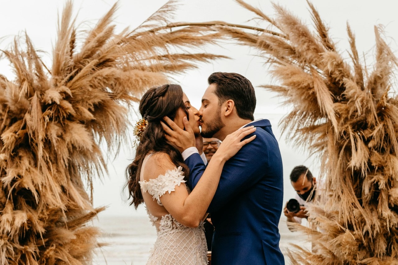 a bride and groom kissing at their wedding altar on a beach in the fall