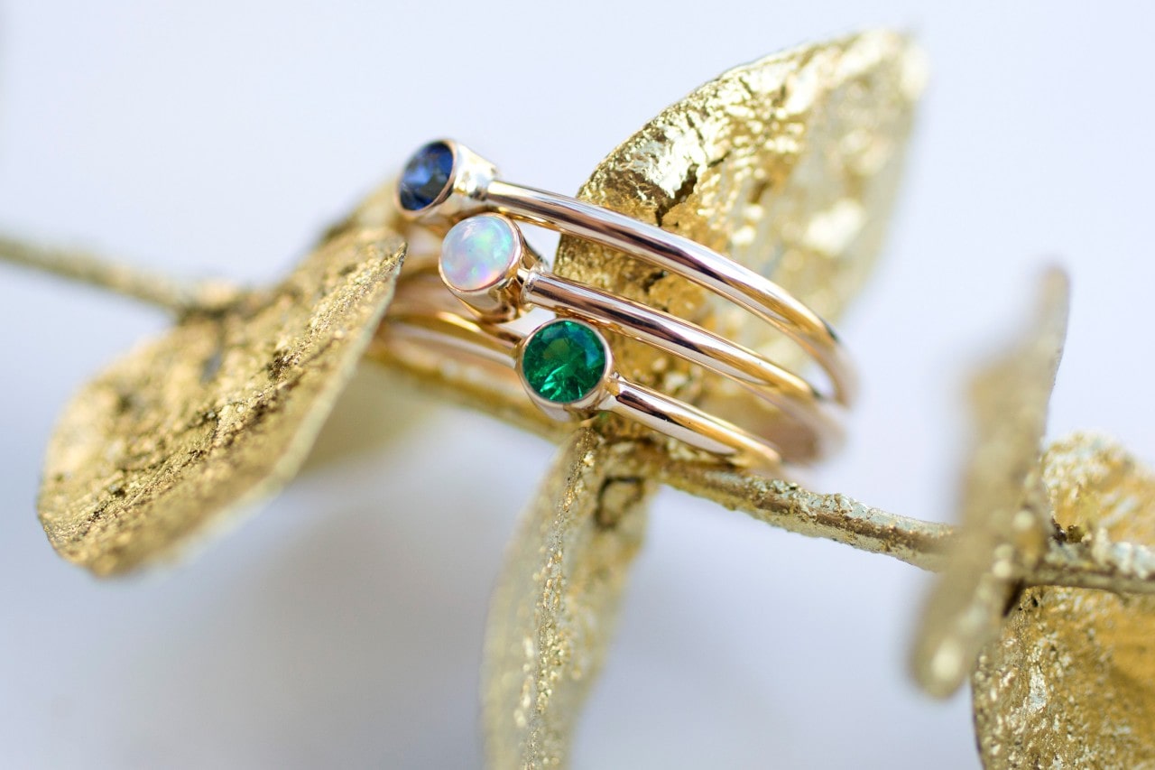 An emerald, opal, and sapphire rings around gold