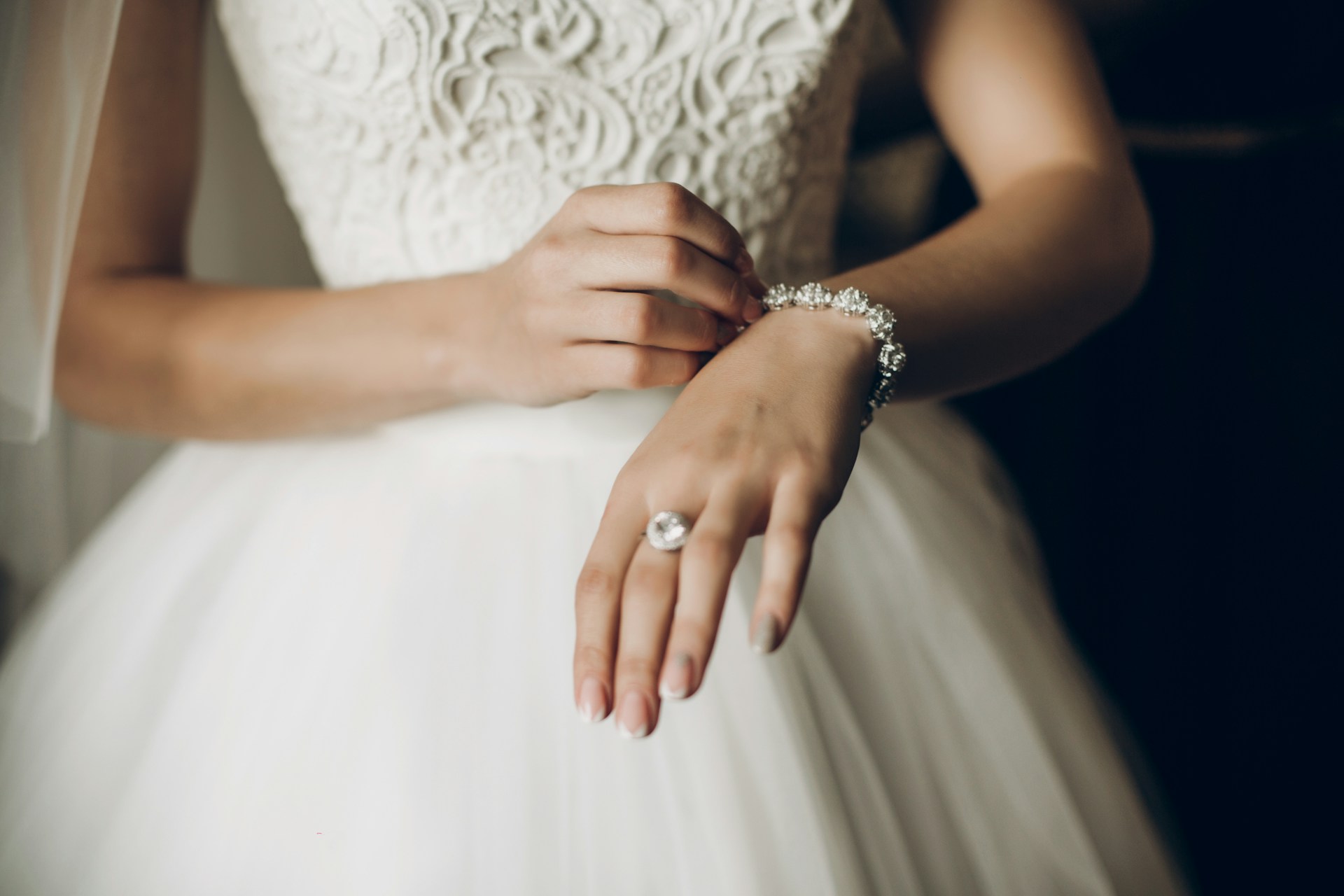 A close-up bride putting a diamond bracelet onto her wrist on her wedding day.