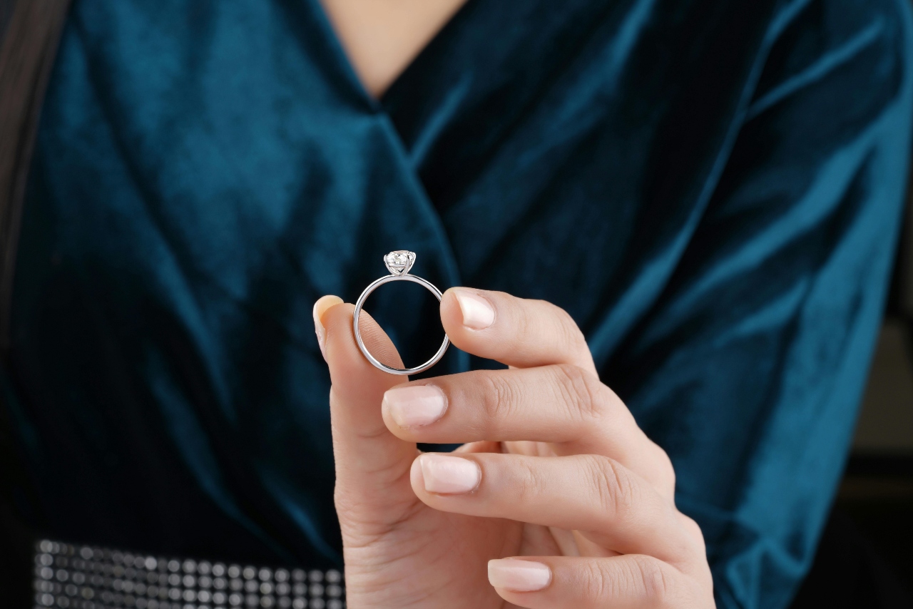 A close-up of a person holding a simple yet elegant solitaire engagement ring.